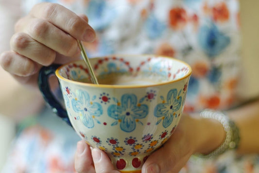woman stirring tea for acid reflux in flowery cup