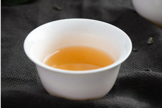 White tea in white cup against black background