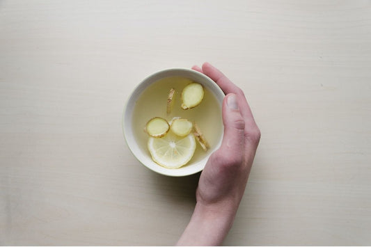 hand holding lemon and ginger tea in a cup